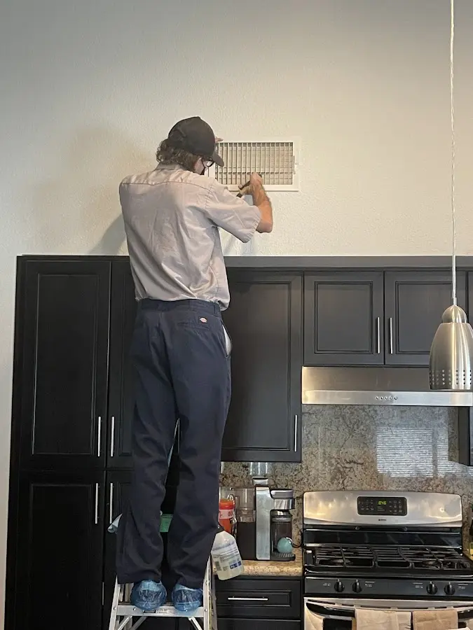 Technician inspecting an air vent during HVAC service in Leeds